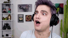 a man with purple hair is wearing headphones and making a face