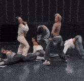 a group of people are dancing on a stage and one of them is singing into a microphone .