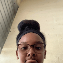 a young girl wearing glasses and a bun looks at the camera