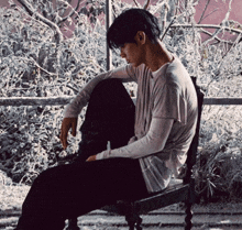 a man in a white shirt sits in a chair looking down