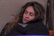 a woman in a black jacket is sitting in front of a screen that says mediaset at the top