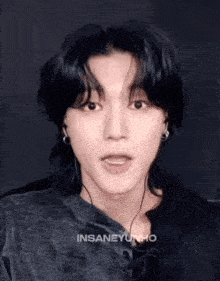 a young man wearing headphones and a black shirt is making a face .