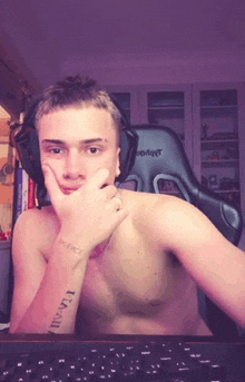 a shirtless man is wearing headphones and has a tattoo on his arm that says i am