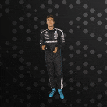 a man in a petronas jumpsuit is jumping in the air