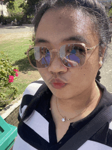 a woman wearing sunglasses has a reflection of herself in the glasses