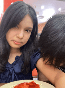 a girl sitting at a table with a plate of spaghetti and ketchup