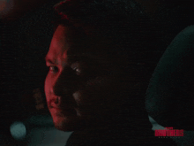 a close up of a man 's face in a dark room with the word brothers on the bottom right