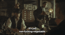 a man sitting at a desk with the words it 's just non-fucking-negotiable above him