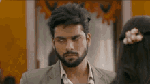 a man with a beard and a suit is looking at a woman .