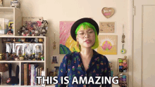 a woman with green hair says this is amazing in front of a bookshelf
