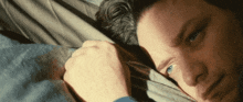 a close up of a man laying down with his head on a pillow
