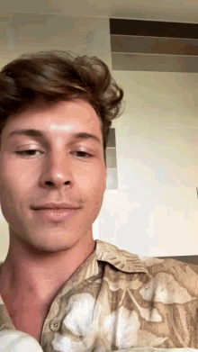 a close up of a man 's face wearing a floral shirt