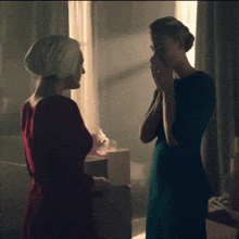 a woman in a red dress is talking to another woman in a blue dress