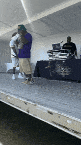 a man in a purple shirt stands on a stage in front of a table that says bess entertainment