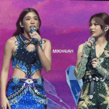 two women singing into microphones with the name mikhiah on the screen