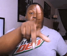 a man wearing a mtn dew shirt is pointing