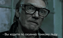 a man wearing glasses and a scarf is looking at the camera with a caption in russian