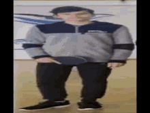 a man in a gray jacket and black pants is holding a table tennis paddle .