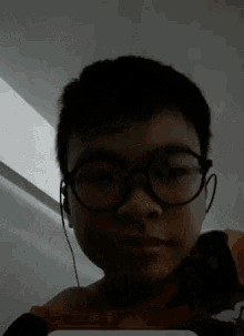 a young boy wearing glasses and earphones looks at the camera