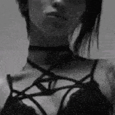 a black and white photo of a woman wearing a choker and bra .