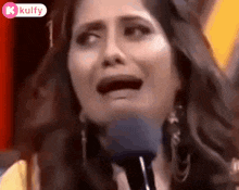 a woman is crying in front of a microphone and making a funny face .