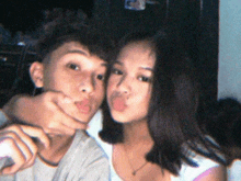 a boy and a girl pose for a picture and the girl is sticking her tongue out