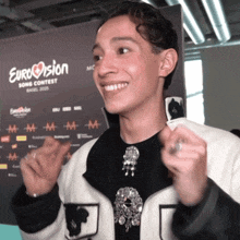 a young man is smiling in front of a sign that says eurovision