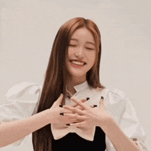 a woman with long hair is smiling with her hands folded