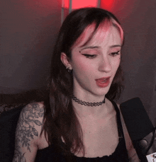 a woman with a tattoo on her arm is singing into a microphone while wearing a choker