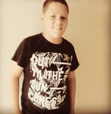 a young boy wearing a black shirt that says " out til the sun comes "