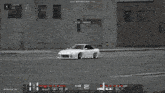a white car is driving down a street in front of a building with the number 324,523 on it