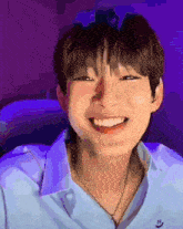 a young man wearing a blue shirt and necklace is smiling .