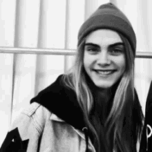 a black and white photo of a woman wearing a beanie and a jacket