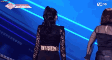 a woman in a black lace dress is standing on a stage in front of a mnet logo ..