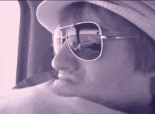 a woman wearing a hat and sunglasses looks out a window