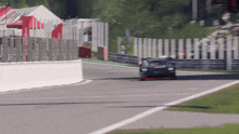a blurred image of a race car on a track with a red banner that says ' hyundai ' on it