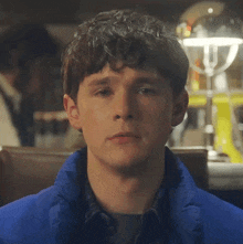 a man wearing a blue jacket looks at the camera