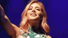 a woman with pink hair is smiling with her arms outstretched