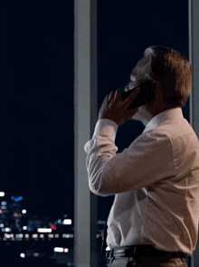 a man in a white shirt is talking on his cell phone