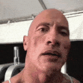 a close up of a man 's face with a bald head and a tattoo on his chest .