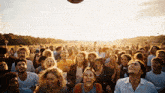 a crowd of people laughing and watching a ball being thrown in the air by veo