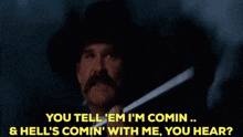 a man in a cowboy hat holds a gun and says " you tell ' em i 'm comin "