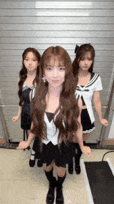 three girls are standing next to each other in front of a white wall