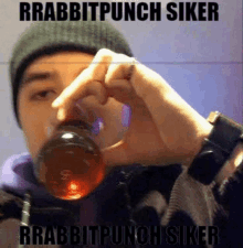 a man in a beanie is drinking from a bottle that says rabbitpunch siker