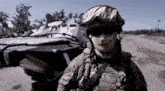 a soldier wearing a helmet and sunglasses is standing in front of a military vehicle