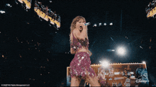 a woman in a pink dress is singing into a microphone in front of a disney logo