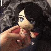 a person is holding a stuffed doll with a red cape on it .