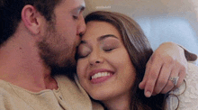 a man is kissing a woman on the cheek while the woman is smiling .