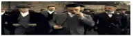 a group of men in suits are walking down a street and one man is smoking a cigarette .
