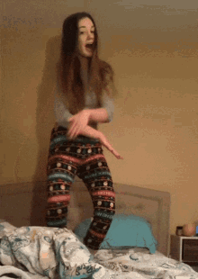 a woman in pajamas jumps on a bed